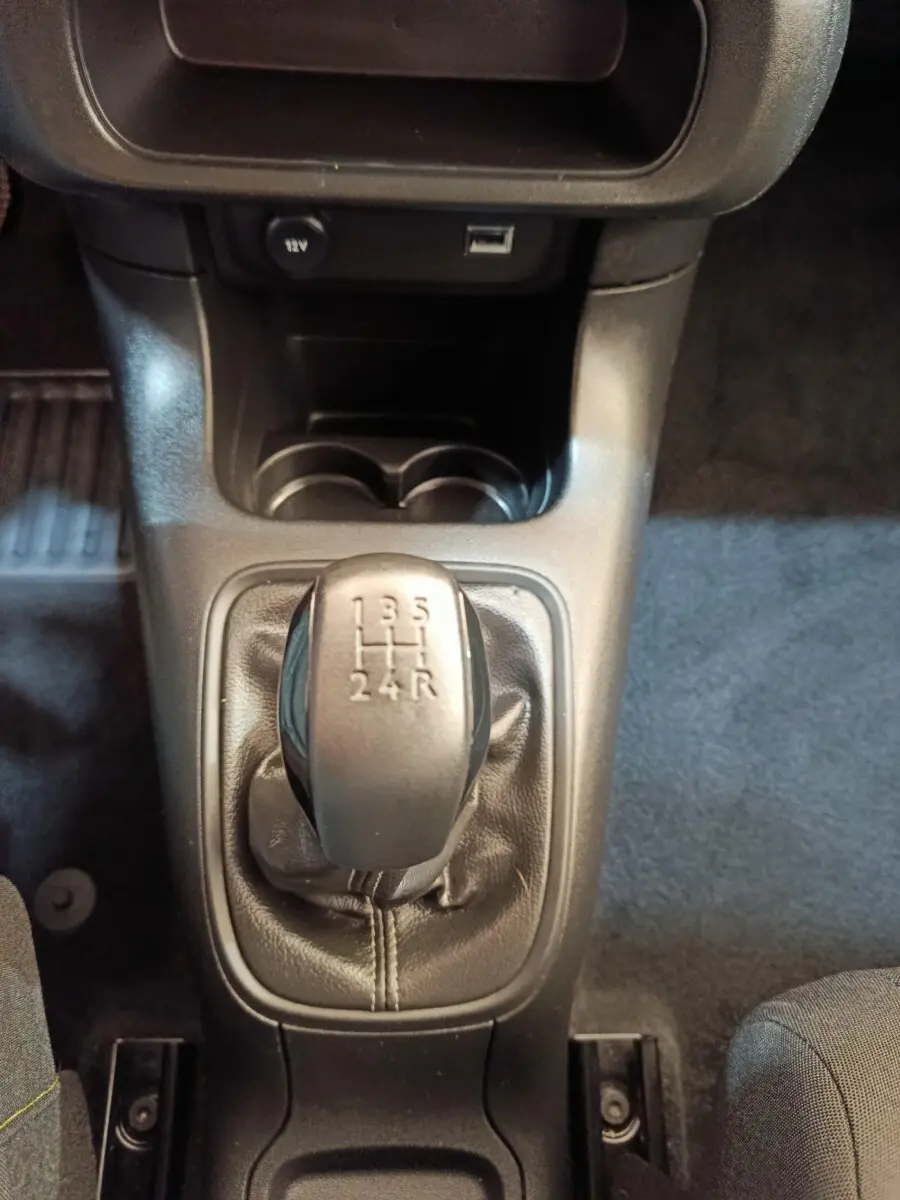 Gros plan sur le levier de vitesse manuel noir de la Citroën C3 PureTech 83 BVM PLUS 2024, intérieur gris foncé.