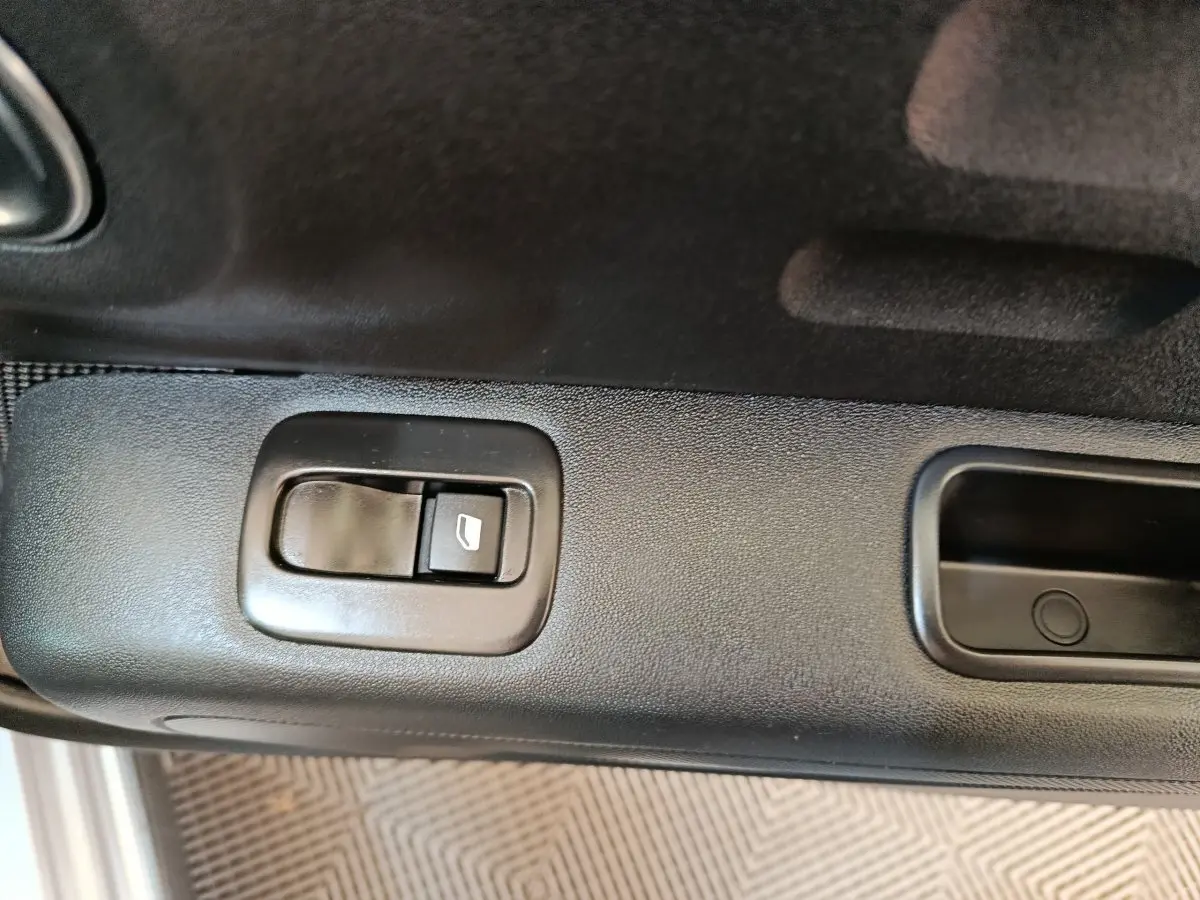 Gros plan sur le bouton de commande de la vitre côté conducteur d'une Citroën C3 gris foncé, intérieur noir.