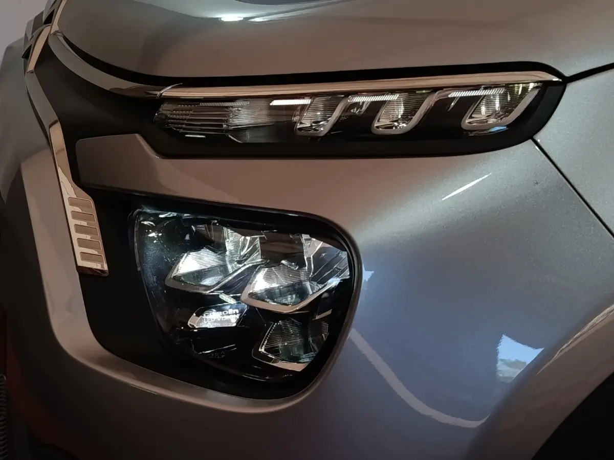 Gros plan sur le phare avant droit gris foncé d'une Citroën C3 2024 avec signature lumineuse LED distinctive.