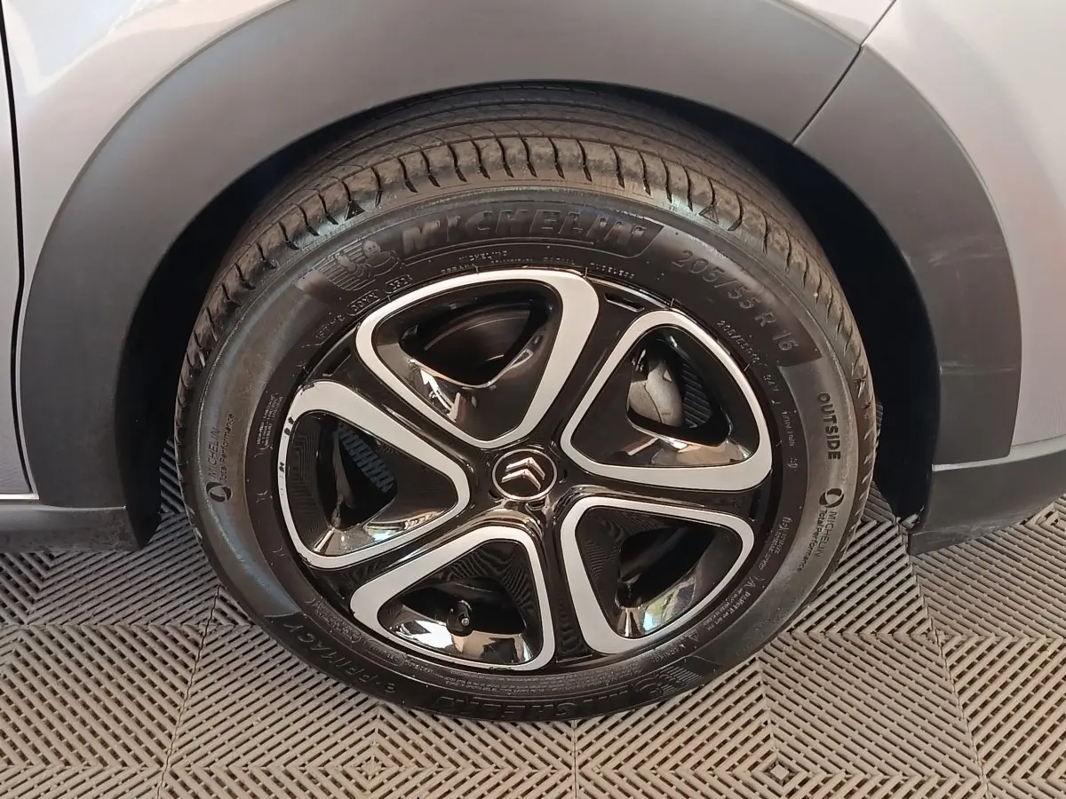 Gros plan sur la roue avant droite d'une Citroën C3 gris foncé, avec jante alliage noire et argentée au design moderne.