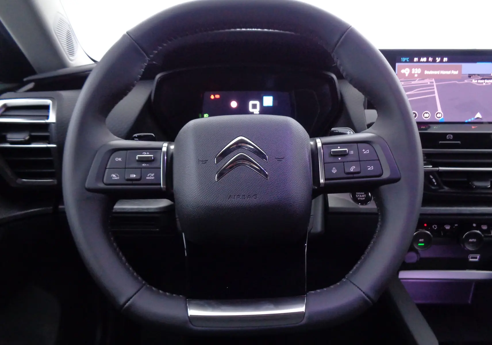 Vue rapprochée du volant cuir noir du Citroën C5 X 2023 avec commandes intégrées et tableau de bord numérique.