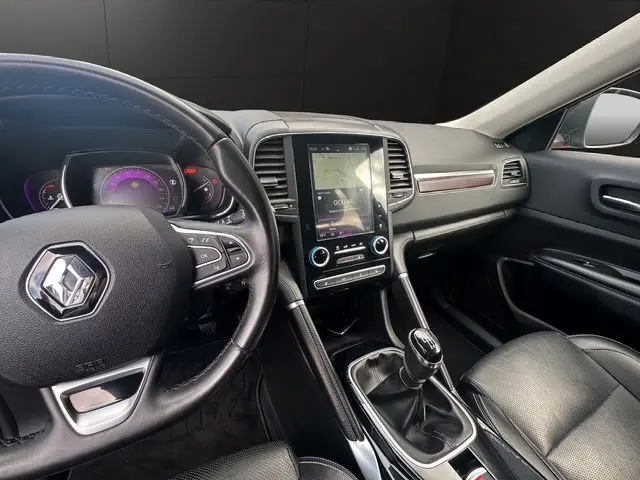 Intérieur noir du Renault Koleos 2017, vue du poste de conduite avec volant cuir, écran tactile et boîte manuelle.