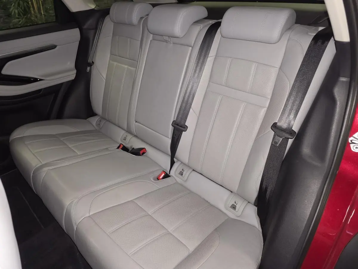 Vue intérieure des sièges arrière en cuir gris clair du Range Rover Evoque rouge, avec ceintures de sécurité visibles.