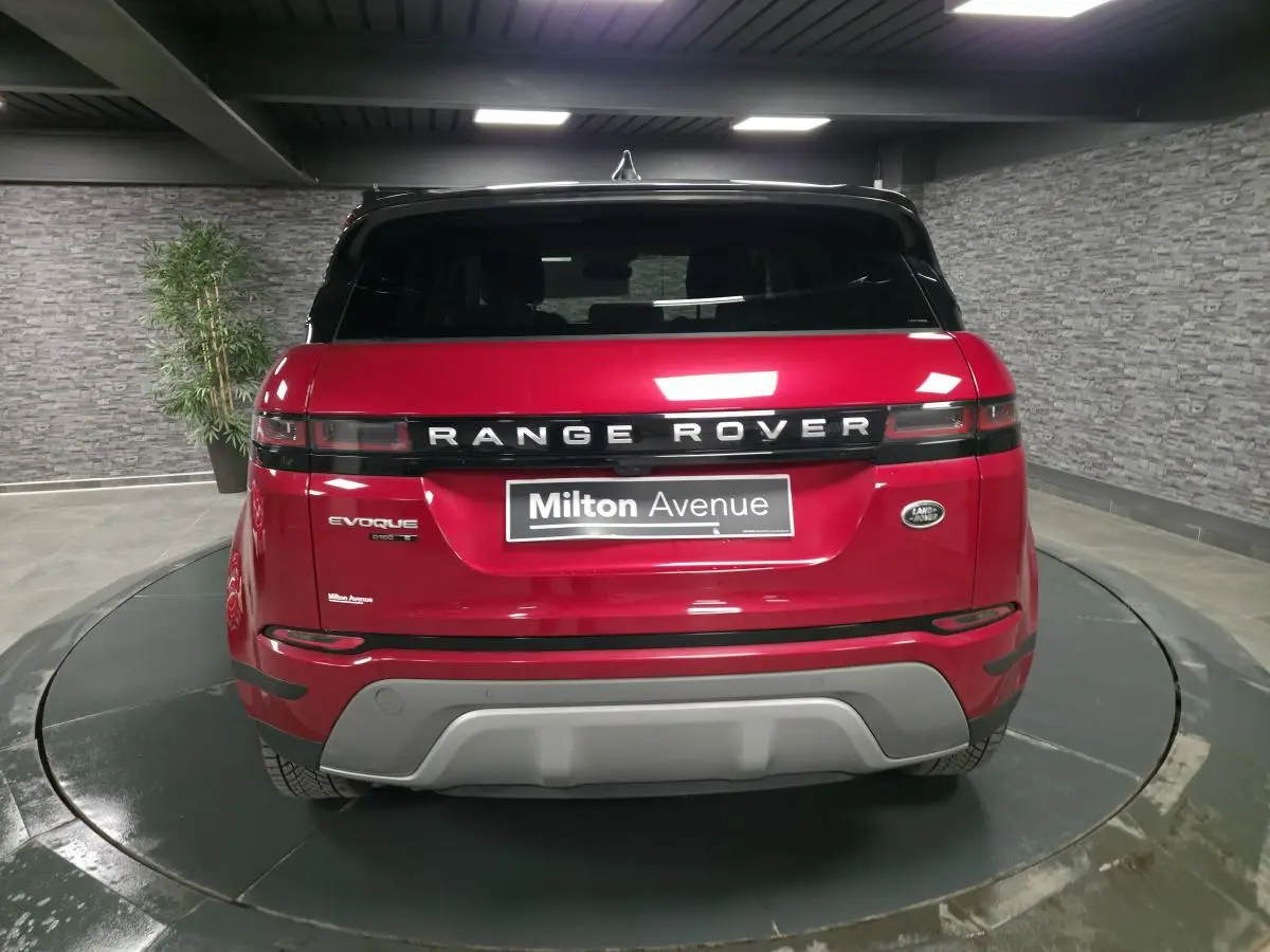 Vue arrière d'un Range Rover Evoque rouge avec toit noir et logo distinctif dans un showroom.