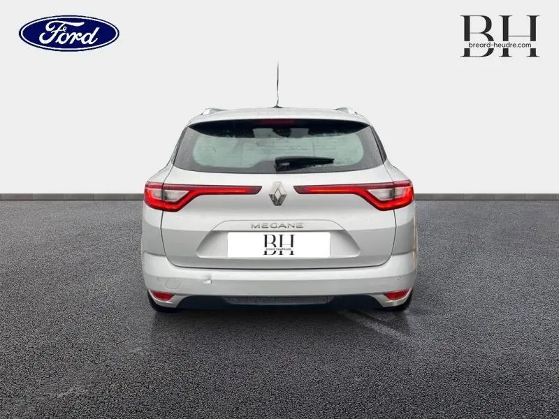 Vue arrière d'une Renault Mégane Break gris platine, avec feux arrière LED étirés et barres de toit visibles.