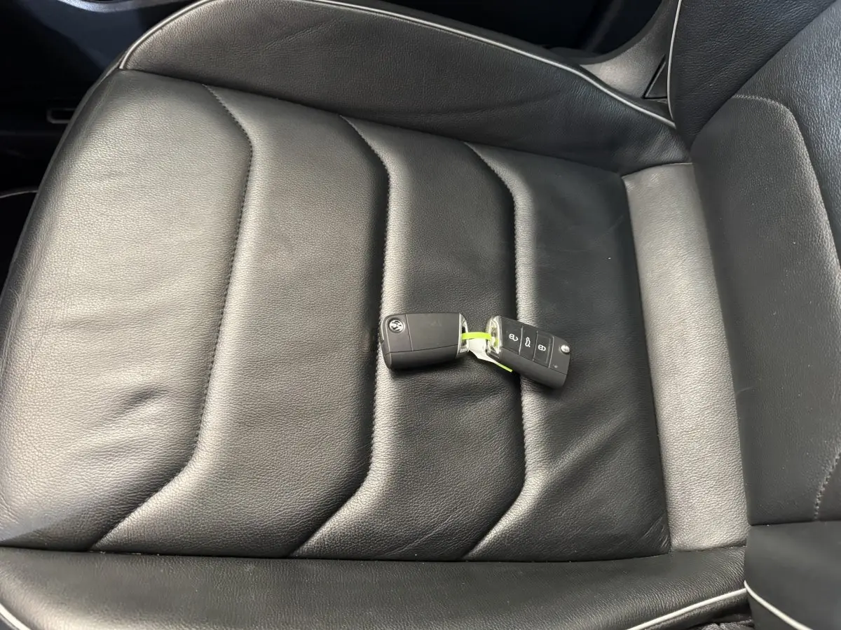 Gros plan sur la clé Volkswagen posée sur le siège en cuir noir côté conducteur du Tiguan Allspace gris foncé.