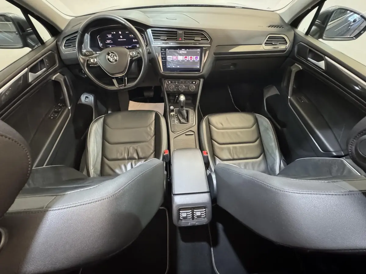Vue intérieure avant du Volkswagen Tiguan Allspace 2019, sièges cuir noirs et écran tactile central visible.