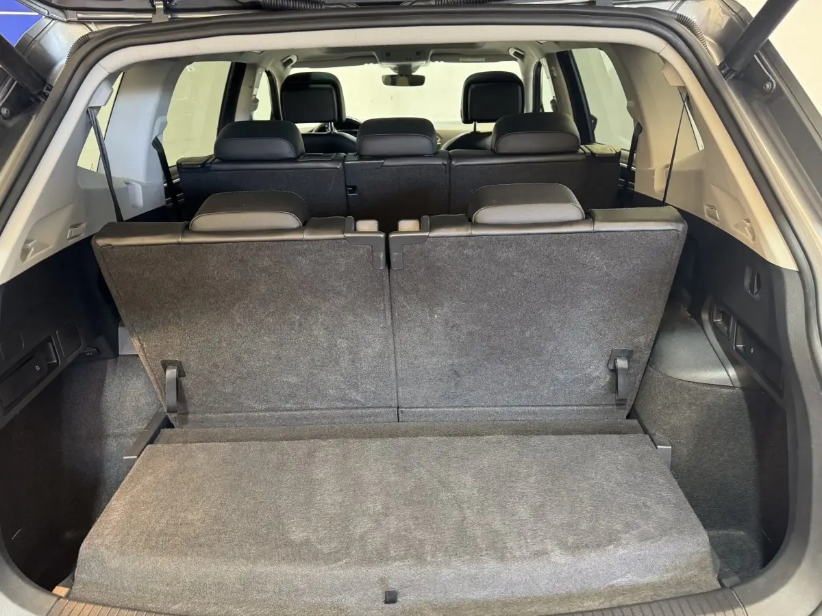 Vue arrière du coffre du Volkswagen Tiguan Allspace gris foncé avec troisième rangée de sièges relevée et banquette arrière visible.