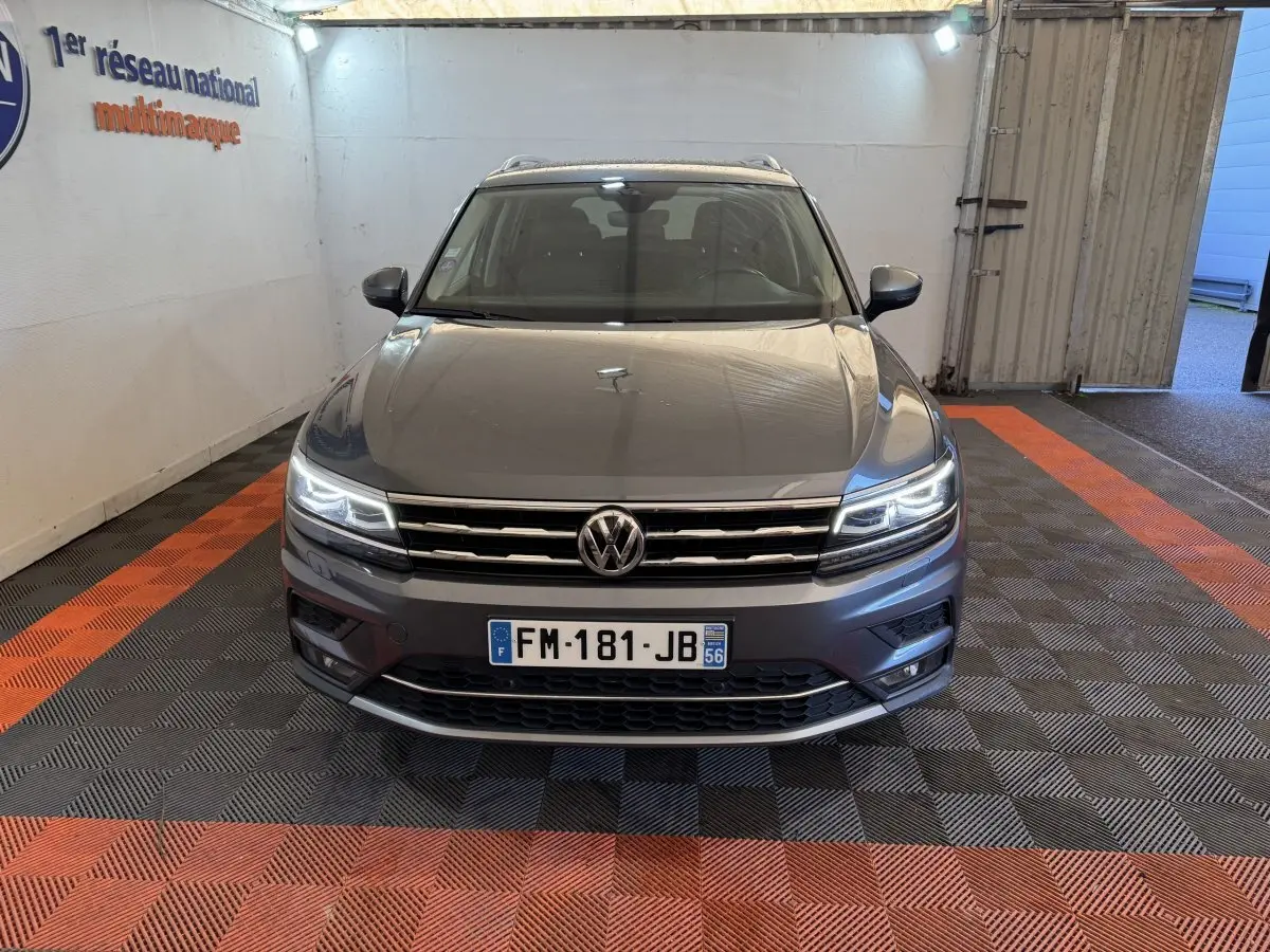 Vue de face du Volkswagen Tiguan Allspace gris foncé avec phares LED allumés dans un garage.