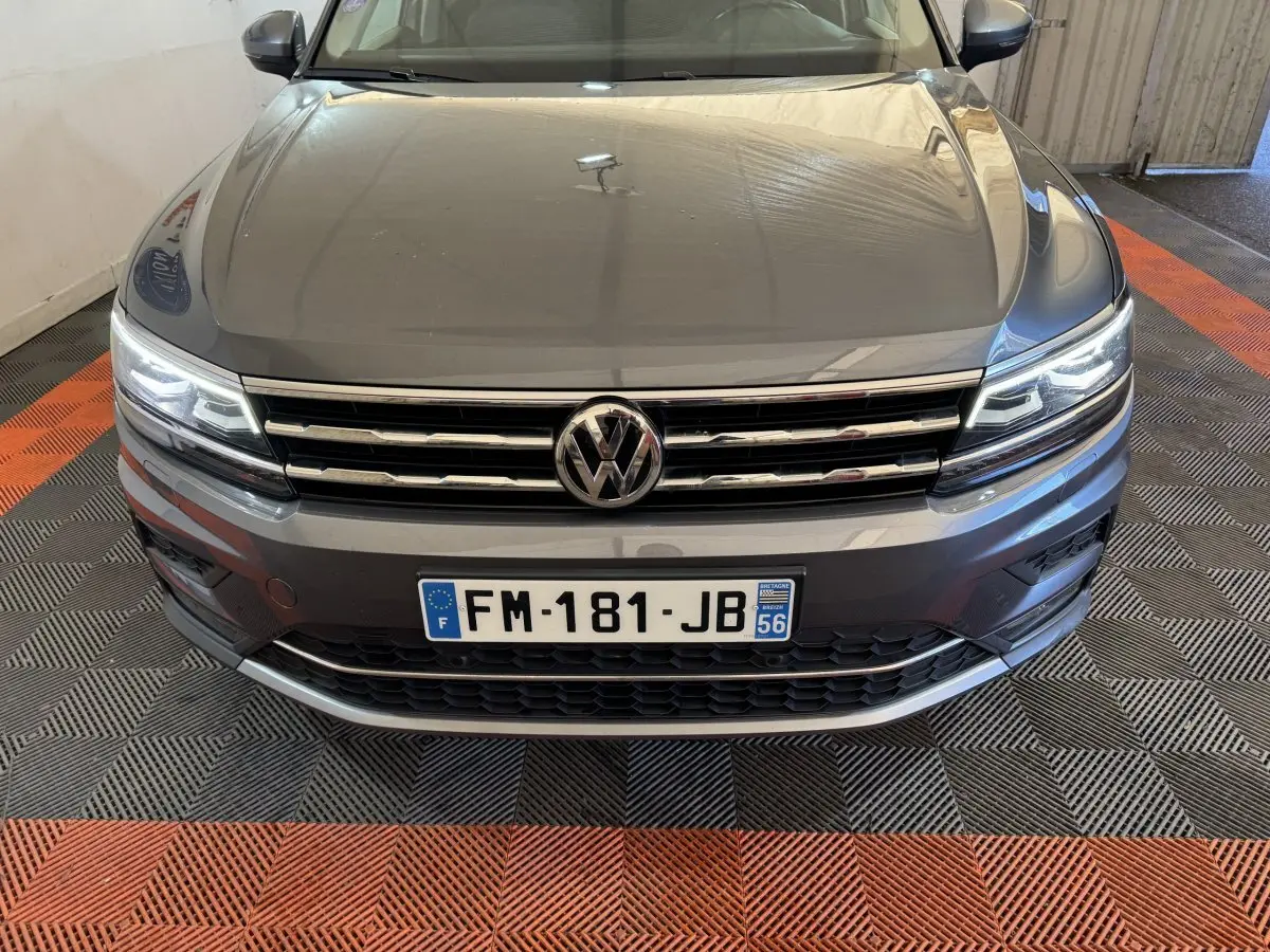 Vue avant rapprochée du Volkswagen Tiguan Allspace gris foncé avec phares LED allumés et calandre chromée.