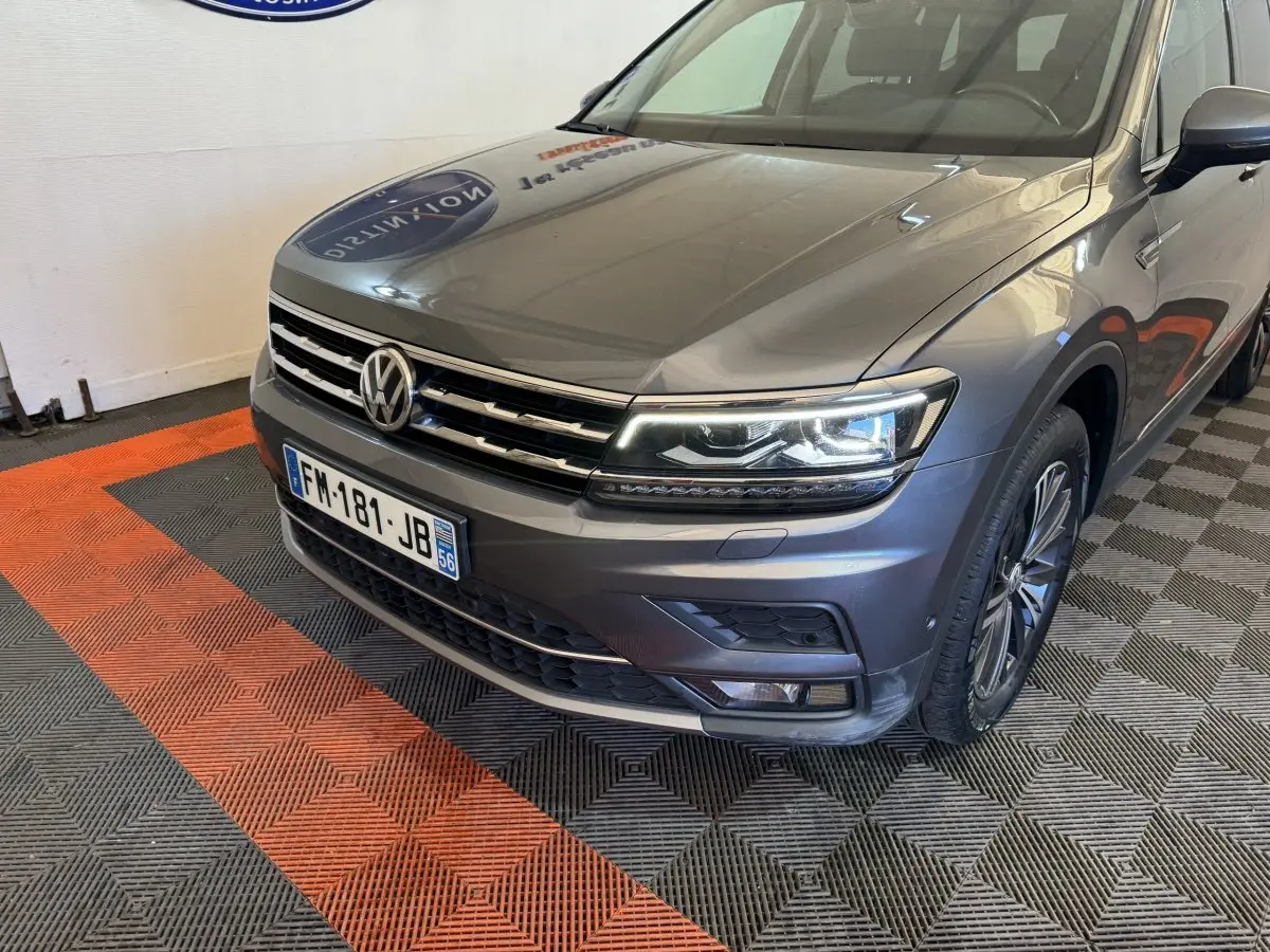 Vue 3/4 avant droit d'un Volkswagen Tiguan Allspace gris foncé avec phares LED et calandre chromée.