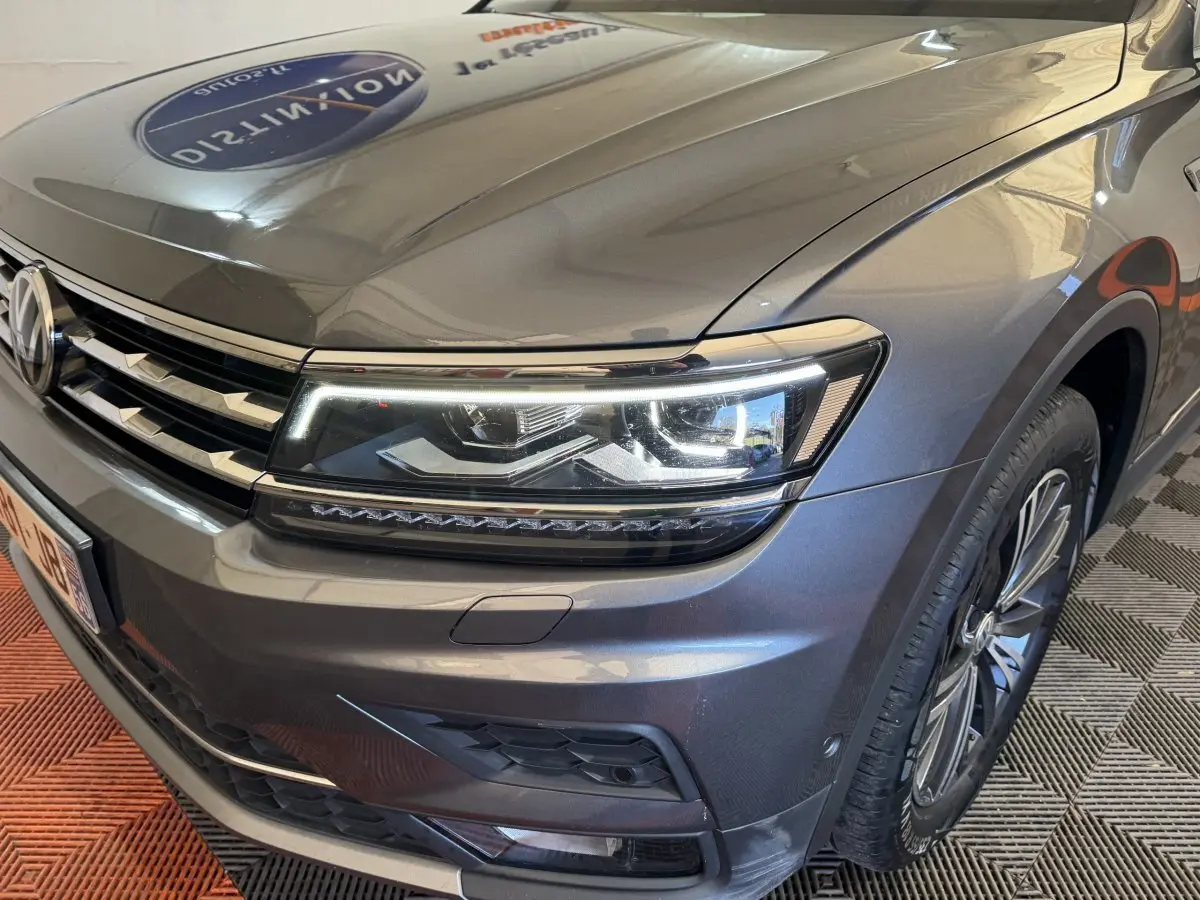 Vue 3/4 avant droit d’un Volkswagen Tiguan Allspace gris foncé avec phares LED et jantes alliage visibles.