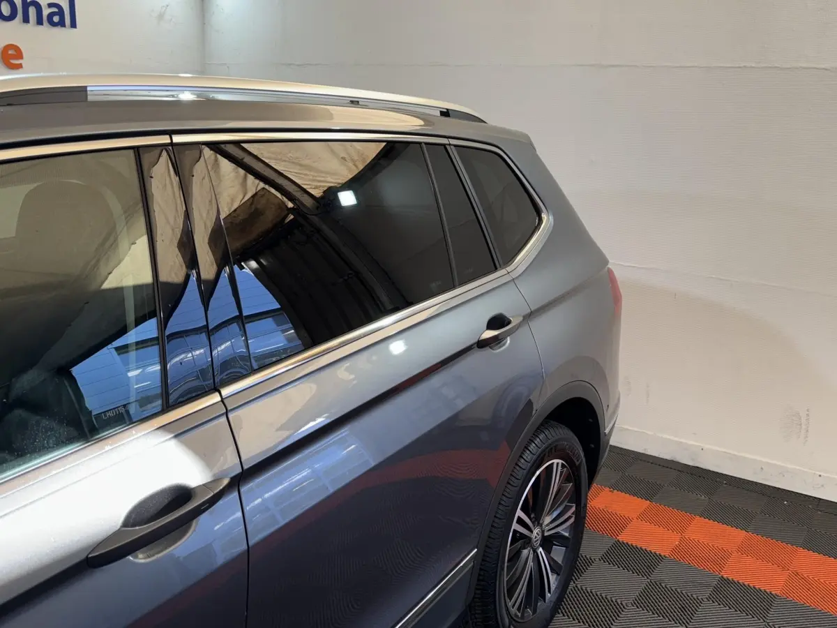 Vue latérale côté droit d'un Volkswagen Tiguan Allspace gris foncé avec jantes alliage et vitres teintées.