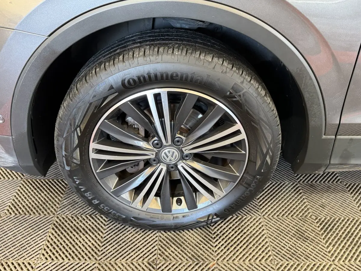 Gros plan sur la roue avant droite d'un Volkswagen Tiguan Allspace gris foncé avec jante alliage distinctive.