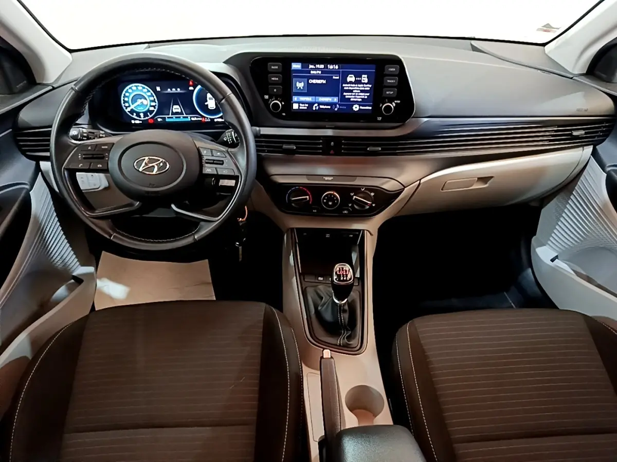 Vue intérieure avant de la Hyundai i20 2022, tableau de bord moderne avec écran tactile et volant cuir multifonctions.