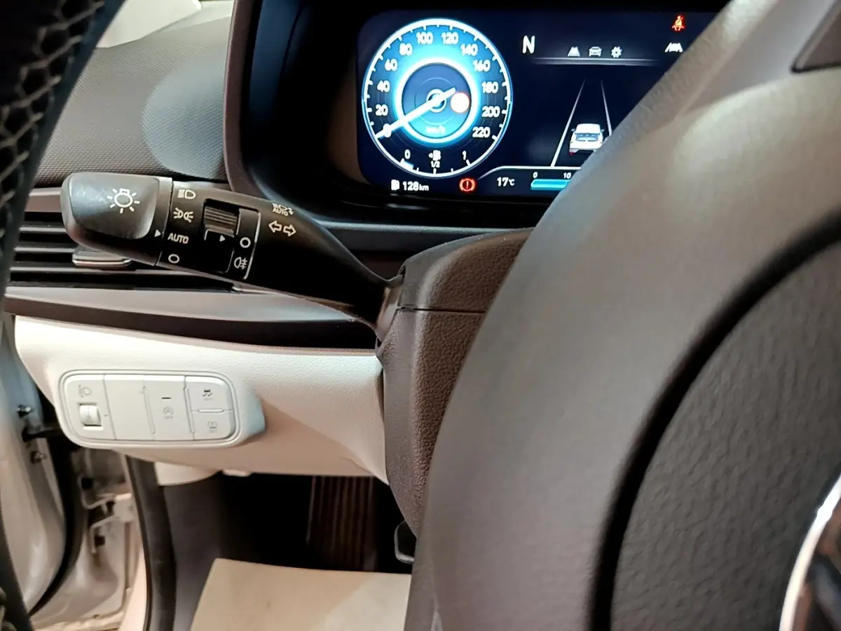 Vue intérieure centrée sur le tableau de bord et volant cuir de la Hyundai i20 gris clair, affichage numérique et commandes éclairage.