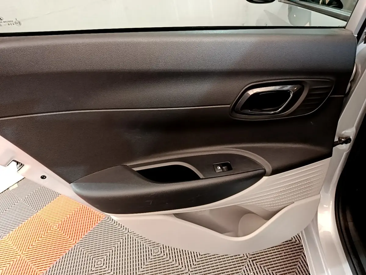 Vue intérieure du panneau de porte avant droit de la Hyundai i20 gris clair, avec commande de vitre électrique.