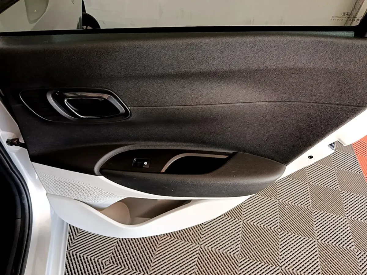 Vue intérieure du panneau de porte avant gauche gris clair de la Hyundai i20 2022 avec poignée et commande de fenêtre.