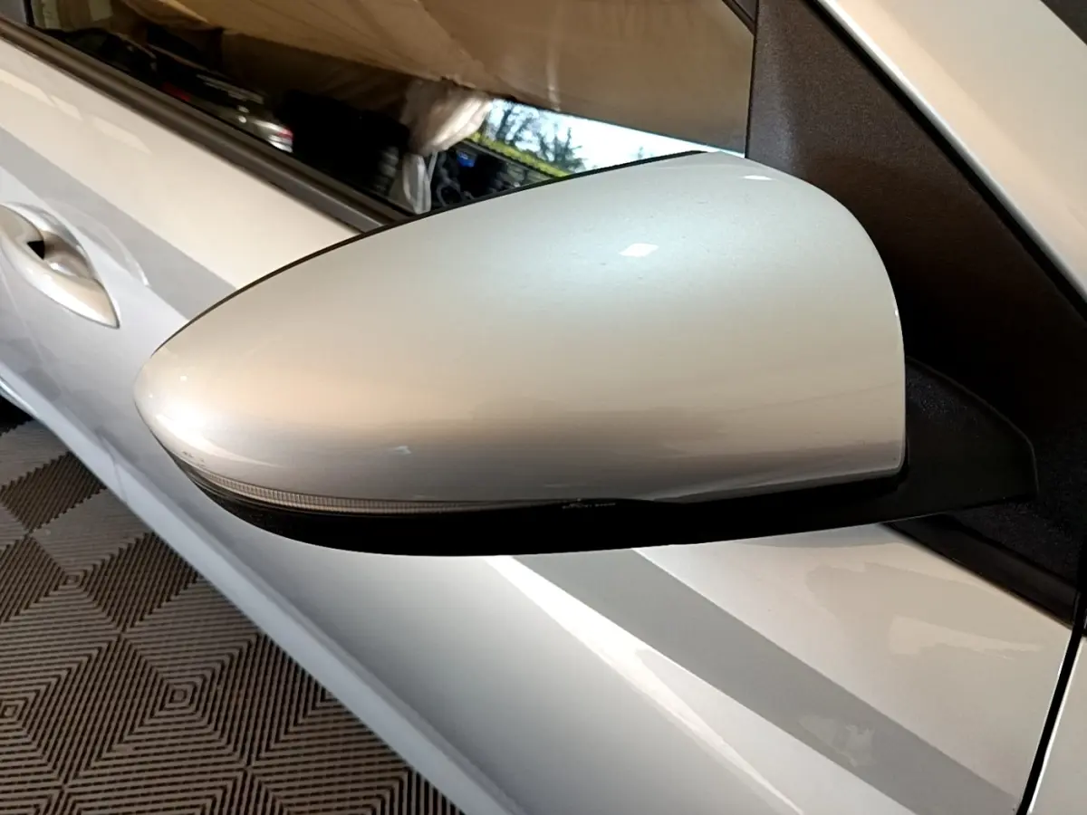 Gros plan sur le rétroviseur côté gauche gris clair de la Hyundai i20 2022, avec la portière visible en arrière-plan.