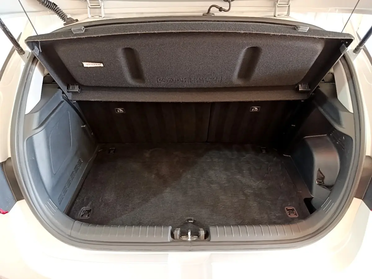 Coffre ouvert vu de l'arrière d'une Hyundai i20 gris clair, montrant l'espace de chargement vide et la tablette amovible.