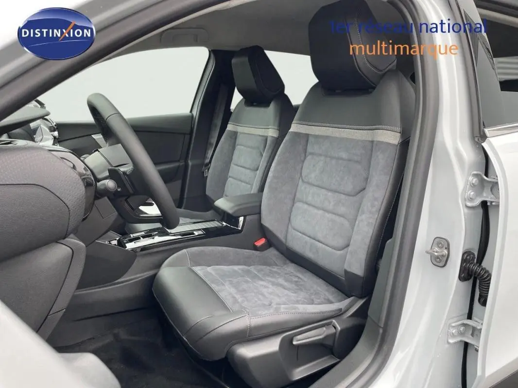 Vue intérieure côté conducteur de la Citroën C4 blanche 2024, sièges en tissu gris et cuir avec console centrale moderne.