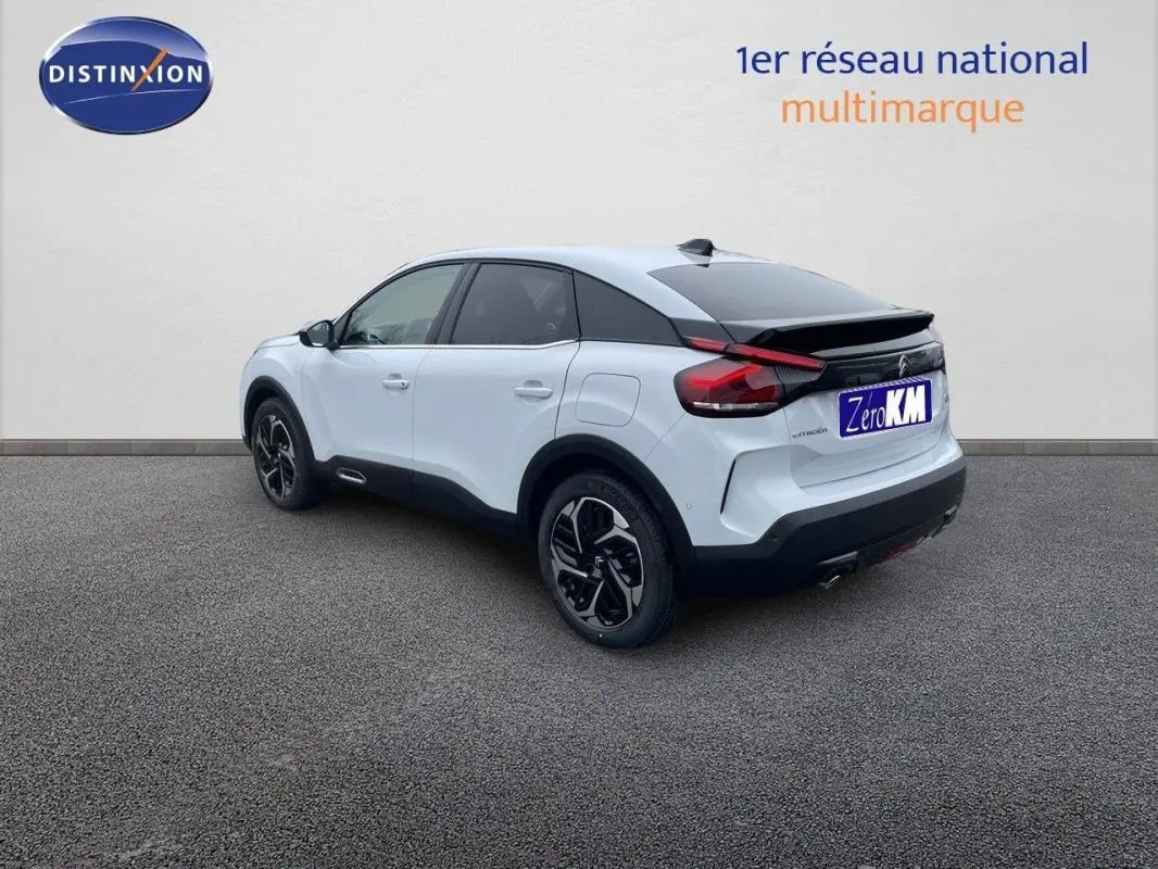 Vue 3/4 arrière droite d'une Citroën C4 blanche 2024 avec jantes aluminium et toit noir contrasté.