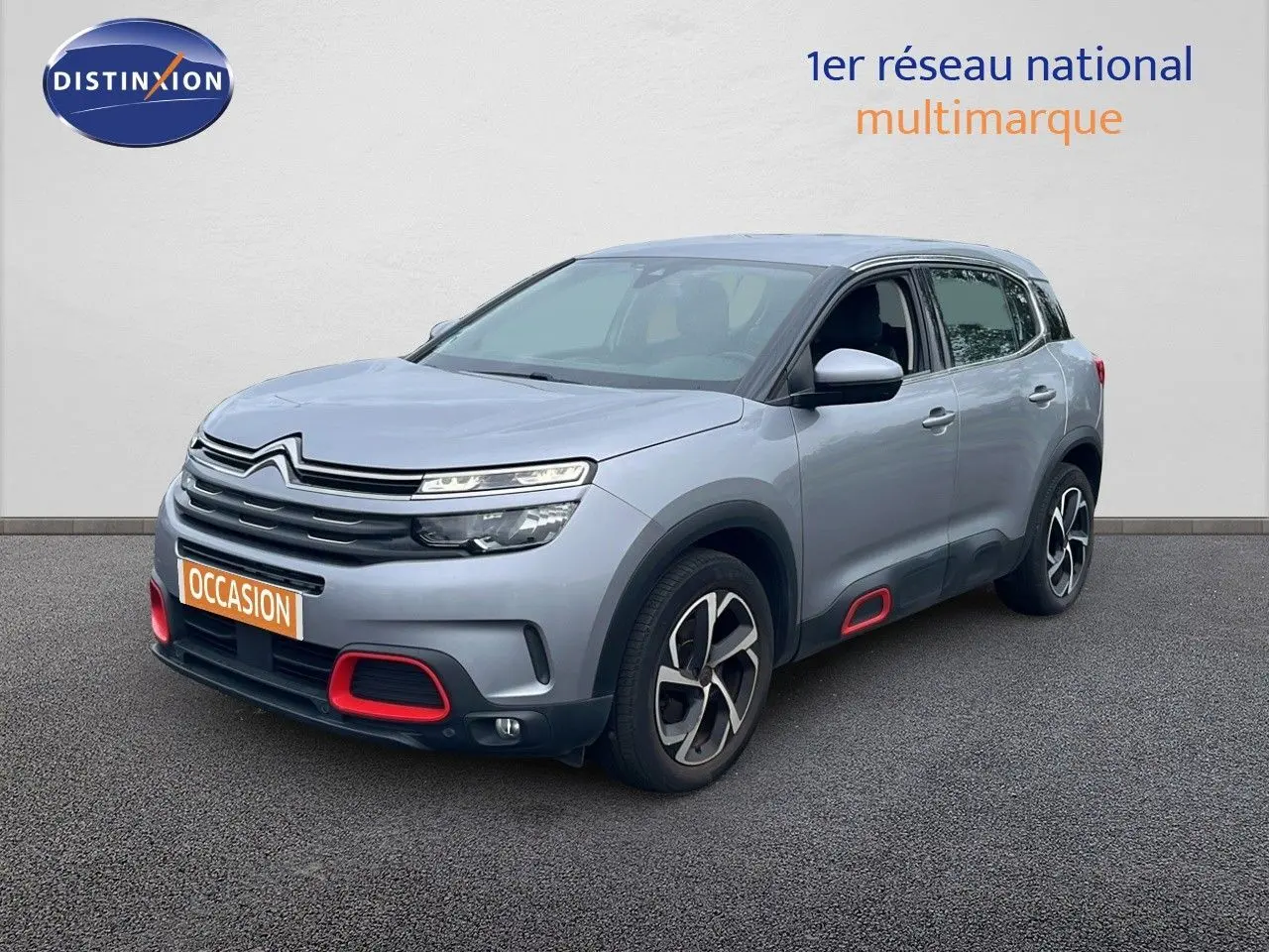 Citroën C5 Aircross gris clair métal en 3/4 avant droit avec détails rouges sur boucliers et bas de caisse.