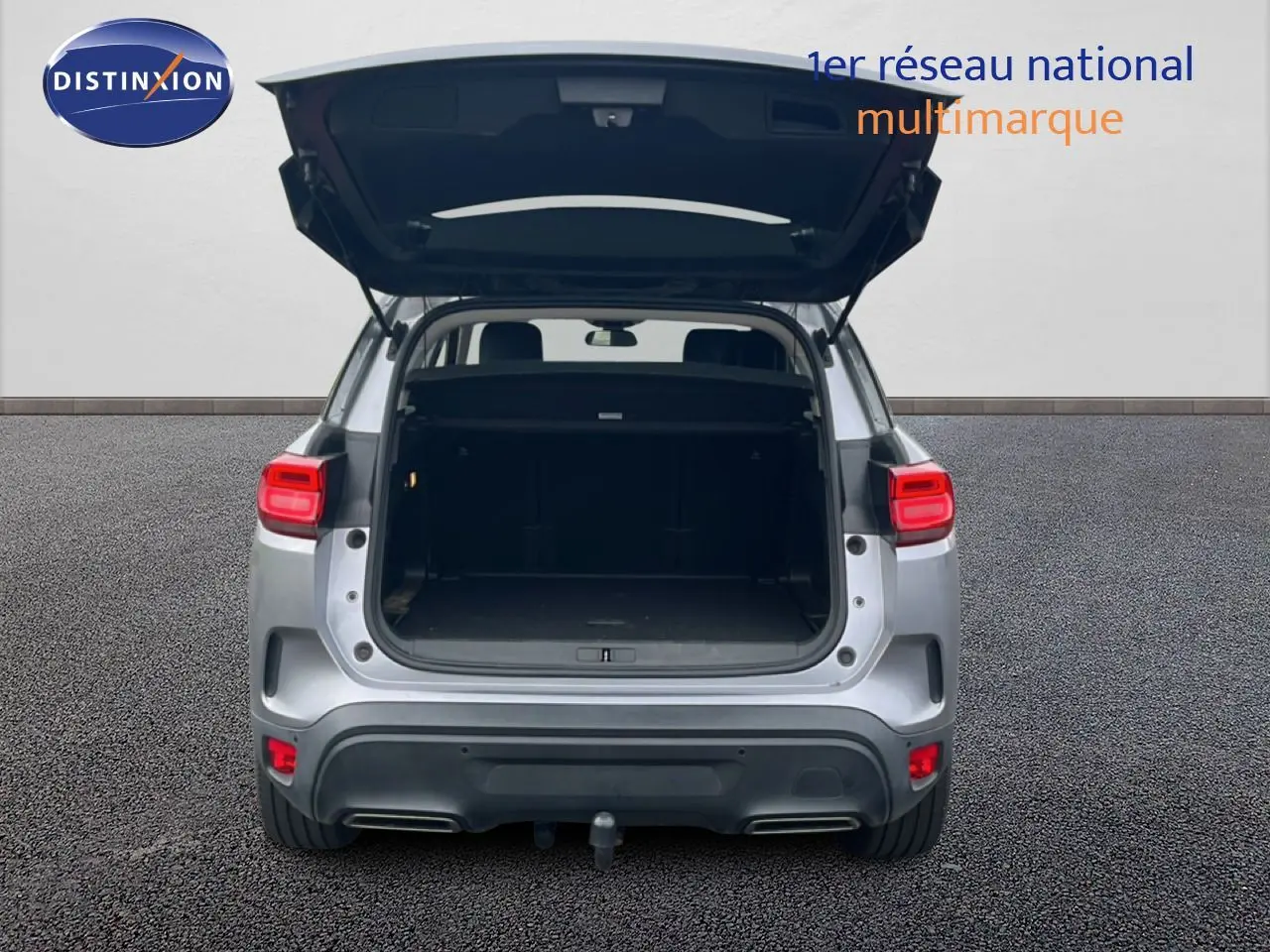 Vue arrière d'un Citroën C5 Aircross gris clair métal avec coffre ouvert, mettant en valeur l'espace de chargement.