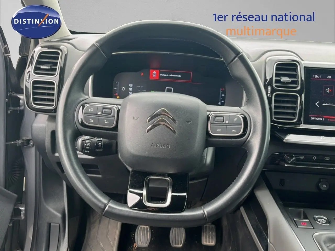 Vue centrée sur le volant noir et le tableau de bord numérique d'une Citroën C5 Aircross gris clair 2020 essence.