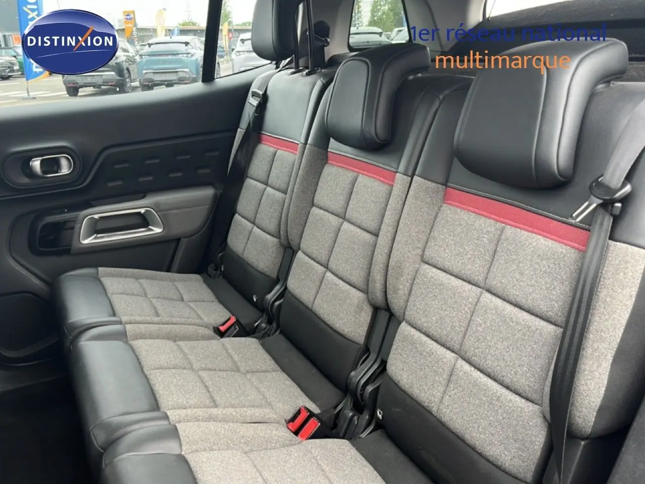 Vue intérieure sur la banquette arrière du Citroën C5 Aircross gris clair, avec sellerie tissu gris et détails rouges.