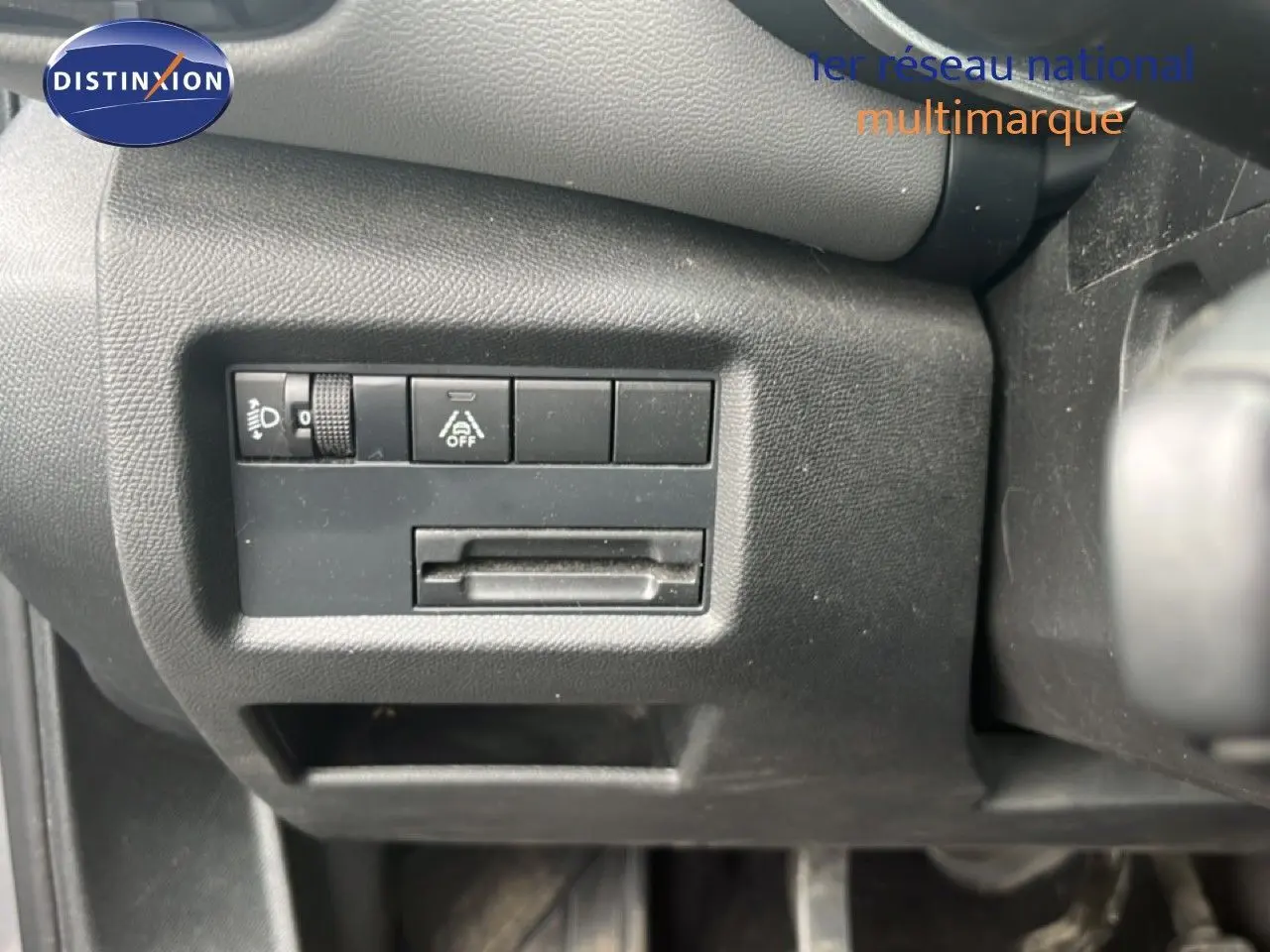 Détail intérieur montrant les commandes de réglage des phares et d'aide à la conduite sur le tableau de bord noir du Citroën C5 Aircross.