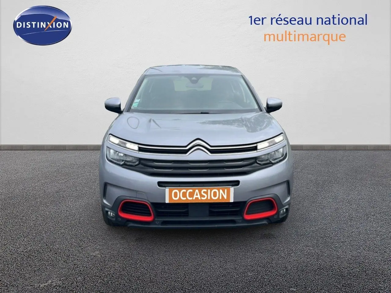 Vue frontale d'un Citroën C5 Aircross gris clair métal avec détails rouges sur le pare-chocs et feux LED allumés.