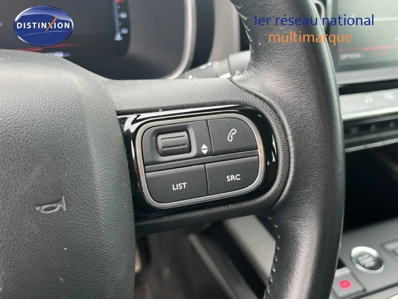 Gros plan sur les commandes multimédia au volant d’un Citroën C5 Aircross gris clair, intérieur 2020.