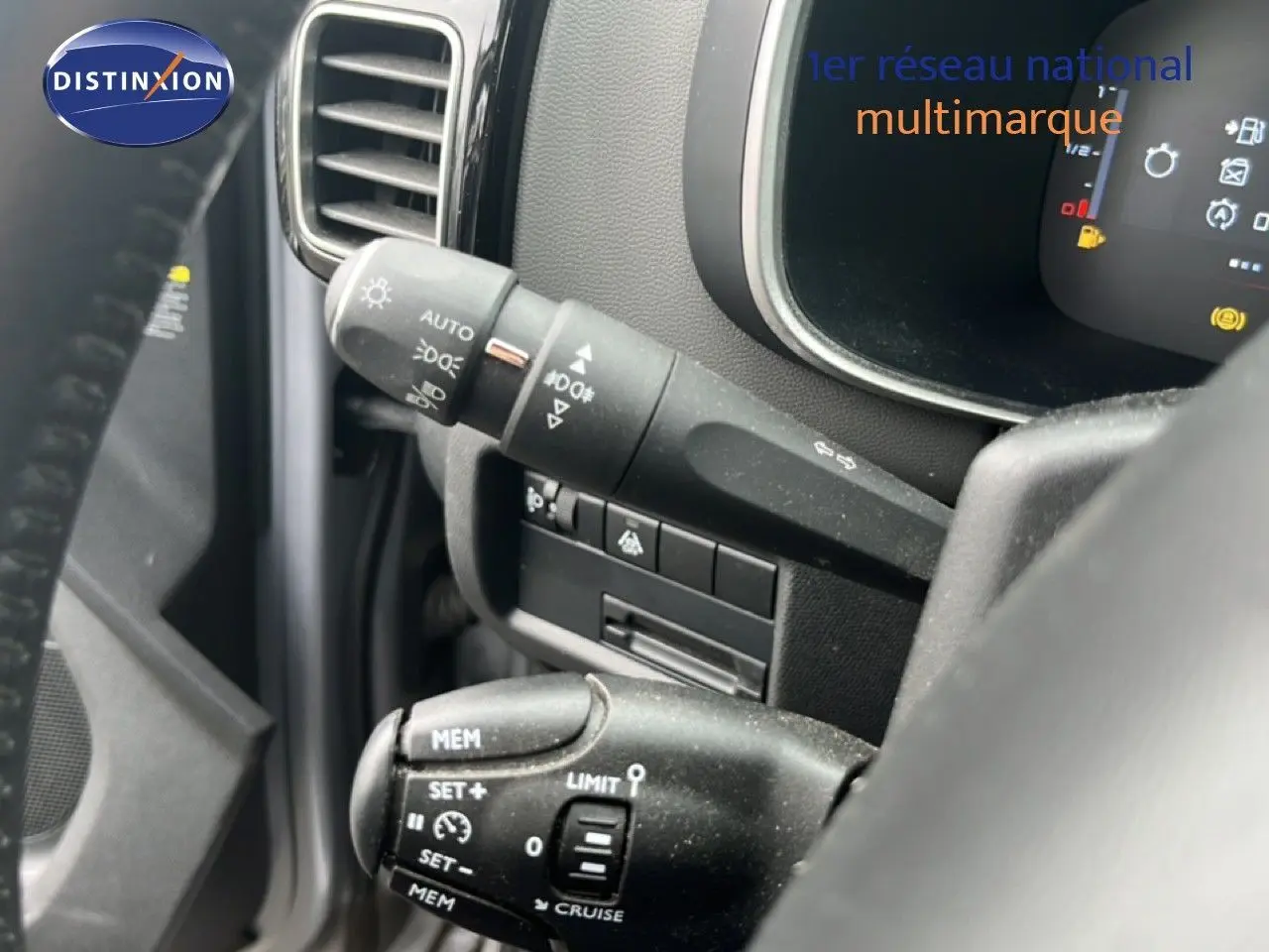 Gros plan sur les commandes au volant du Citroën C5 Aircross gris clair, mettant en valeur les fonctions de régulateur et éclairage.