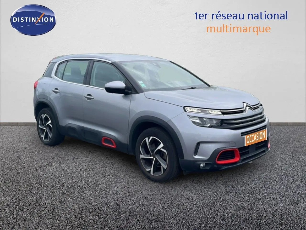 Vue 3/4 avant d’un Citroën C5 Aircross gris clair métal avec détails rouges sur pare-chocs et bas de porte.