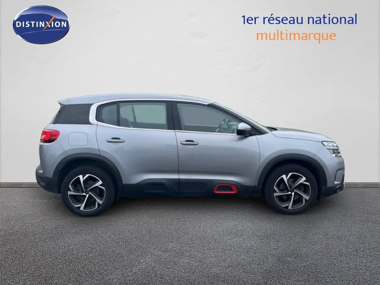 Vue de profil côté gauche d'un Citroën C5 Aircross gris clair métal avec détails noirs et rouge sous les portes.