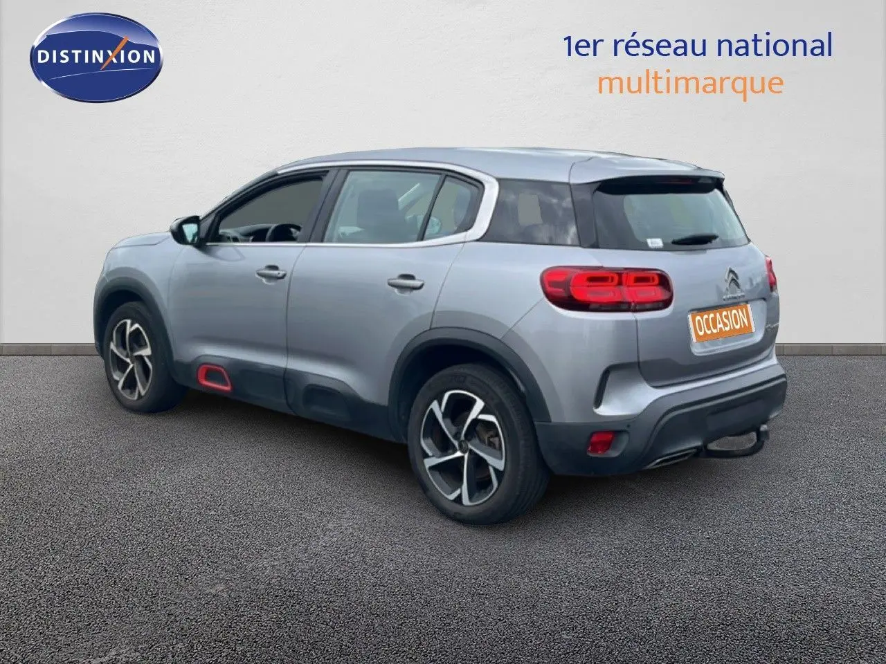 Vue 3/4 arrière droite d'un Citroën C5 Aircross gris clair métal avec jantes alliage et détails rouges sur bas de caisse.