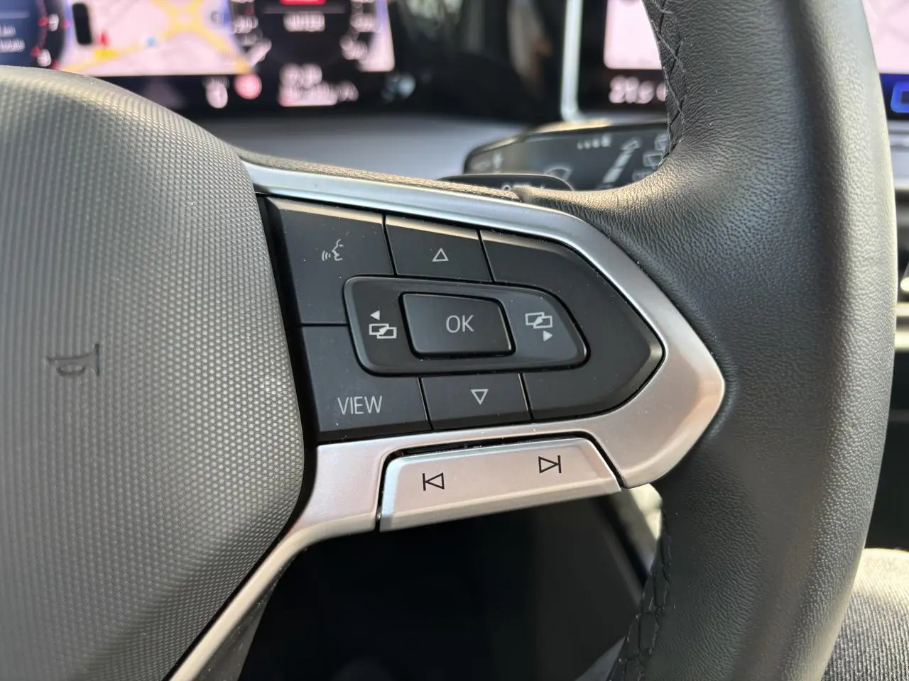 Gros plan sur les commandes à droite du volant noir de la Volkswagen Golf 1.5 eTSI 2024 avec écran digital en arrière-plan.
