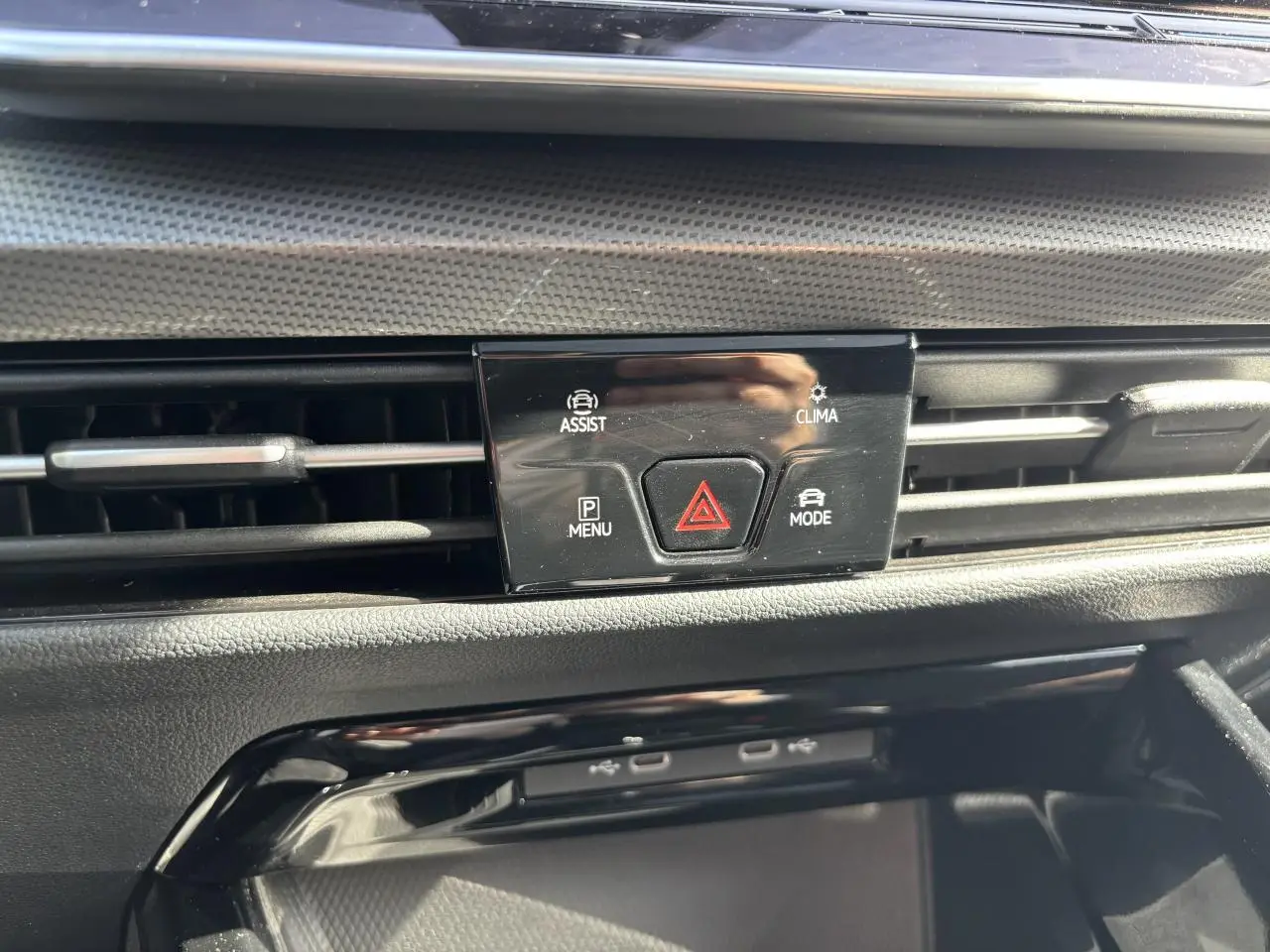 Détail du tableau de bord noir de la Volkswagen Golf 2024 montrant les commandes d'assistance et climatisation.