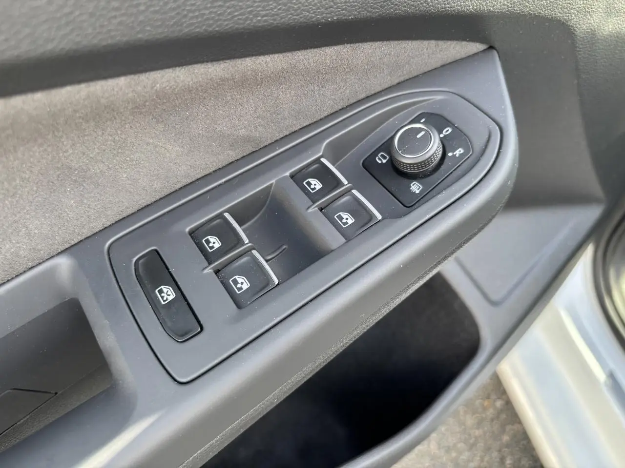 Vue rapprochée des commandes des vitres et des rétroviseurs sur la porte avant gauche d’une Volkswagen Golf blanche 2024.