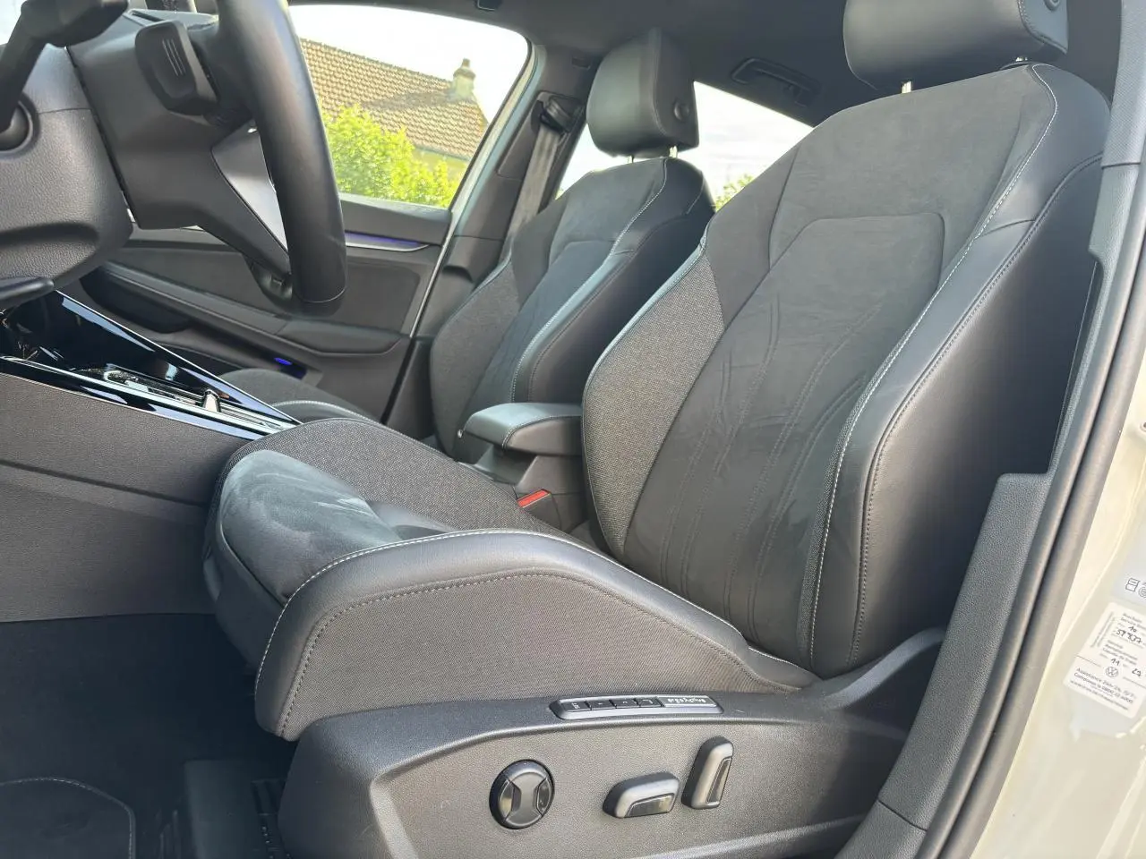 Vue intérieure côté conducteur de la Volkswagen Golf blanche 2024, sièges ergoActive en tissu et cuir avec réglages électriques.