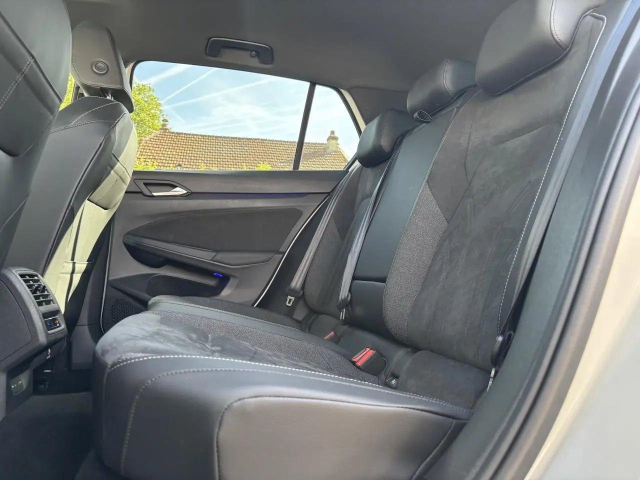 Vue latérale intérieure côté droit des sièges arrière en cuir noir de la Volkswagen Golf 2024 blanche.