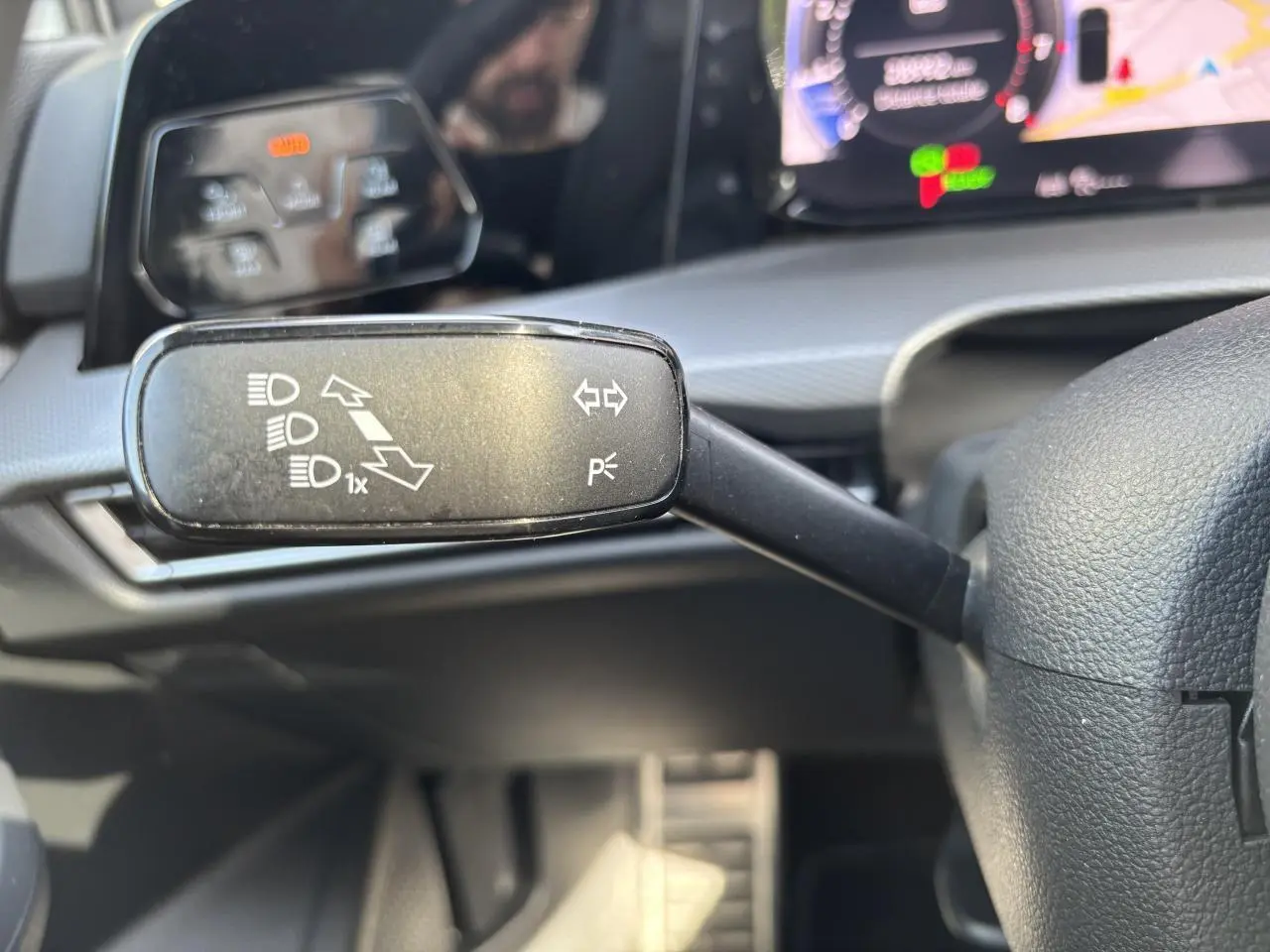 Gros plan sur la commande des feux au volant d’une Volkswagen Golf blanche 2024 avec tableau de bord digital.