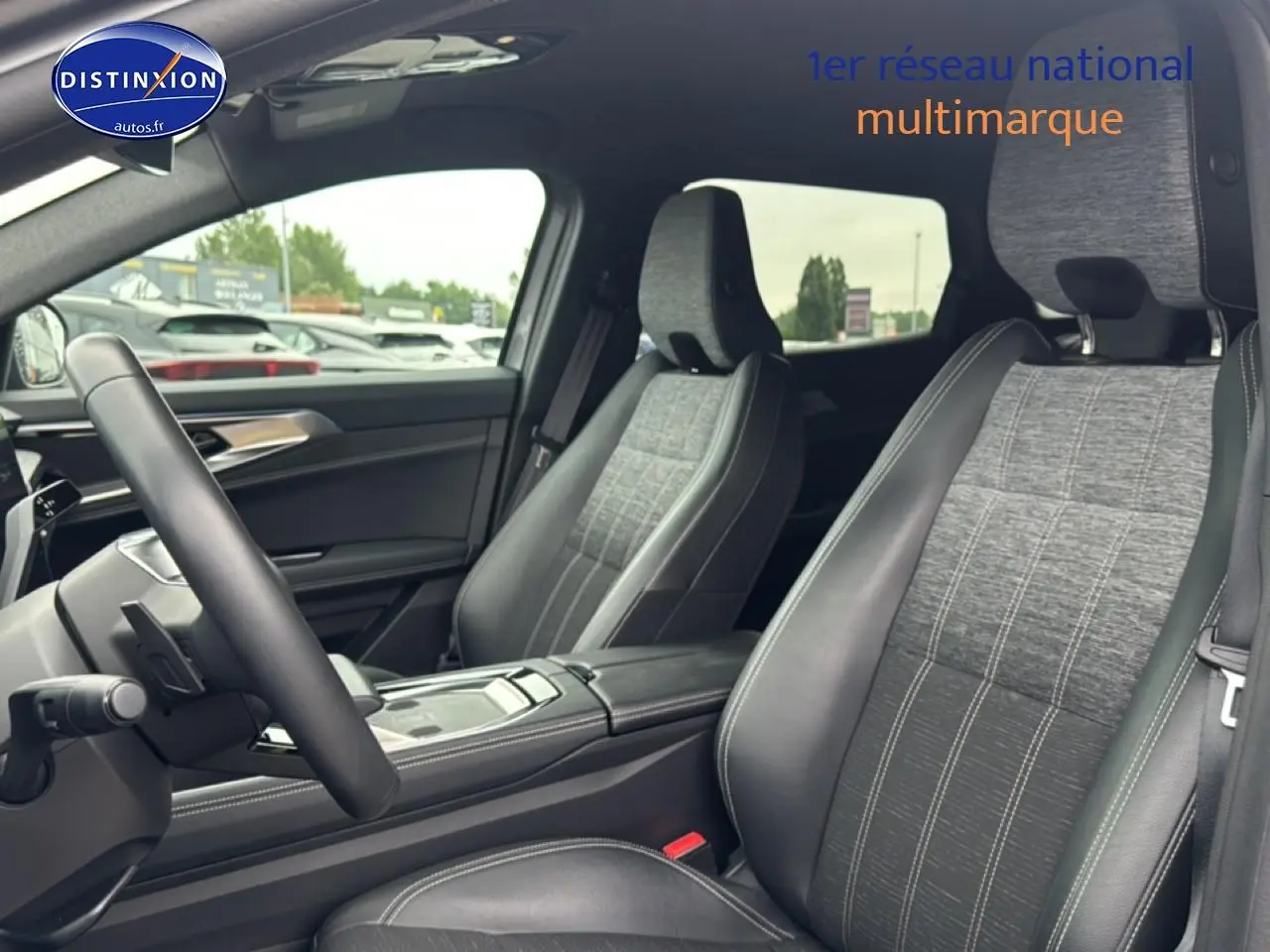 Vue intérieure côté conducteur du Renault Austral 2024, sièges gris tissu et cuir avec accoudoir central noir.