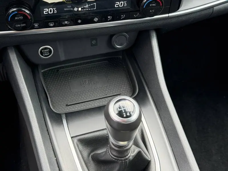 Gros plan sur la console centrale du Nissan Qashqai 2025 gris argile, mettant en valeur le levier de vitesses manuel et les commandes climatiques.