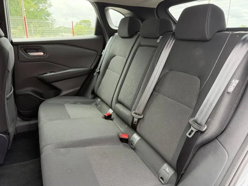 Vue intérieure côté droit sur la banquette arrière noire en tissu du Nissan Qashqai 2025, avec ceintures de sécurité visibles.