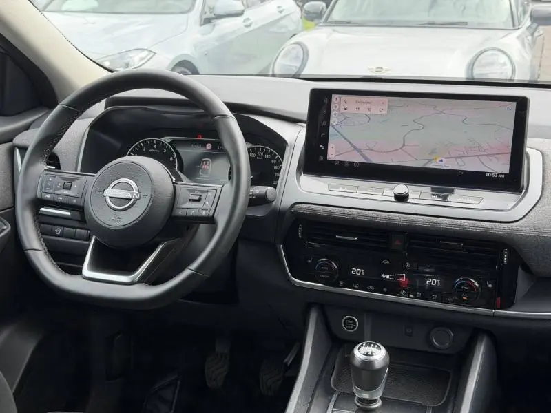 Intérieur du Nissan Qashqai 2025 en vue frontale, volant cuir multifonction et écran tactile GPS affiché.