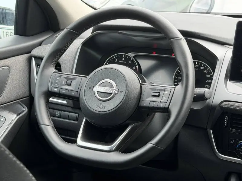 Vue rapprochée du volant cuir multifonction noir du Nissan Qashqai 2025, avec tableau de bord et commandes visibles.