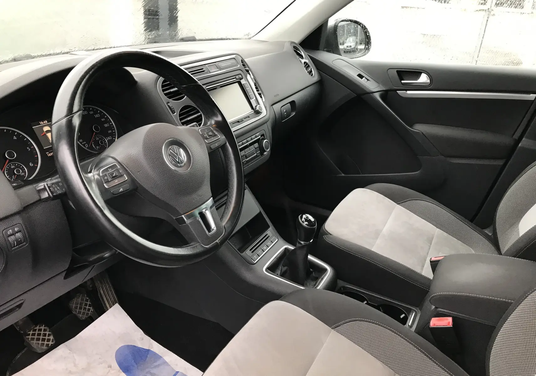 Intérieur noir et gris du Volkswagen Tiguan Sportline 2012, vue côté conducteur avec volant multifonction et boîte manuelle.