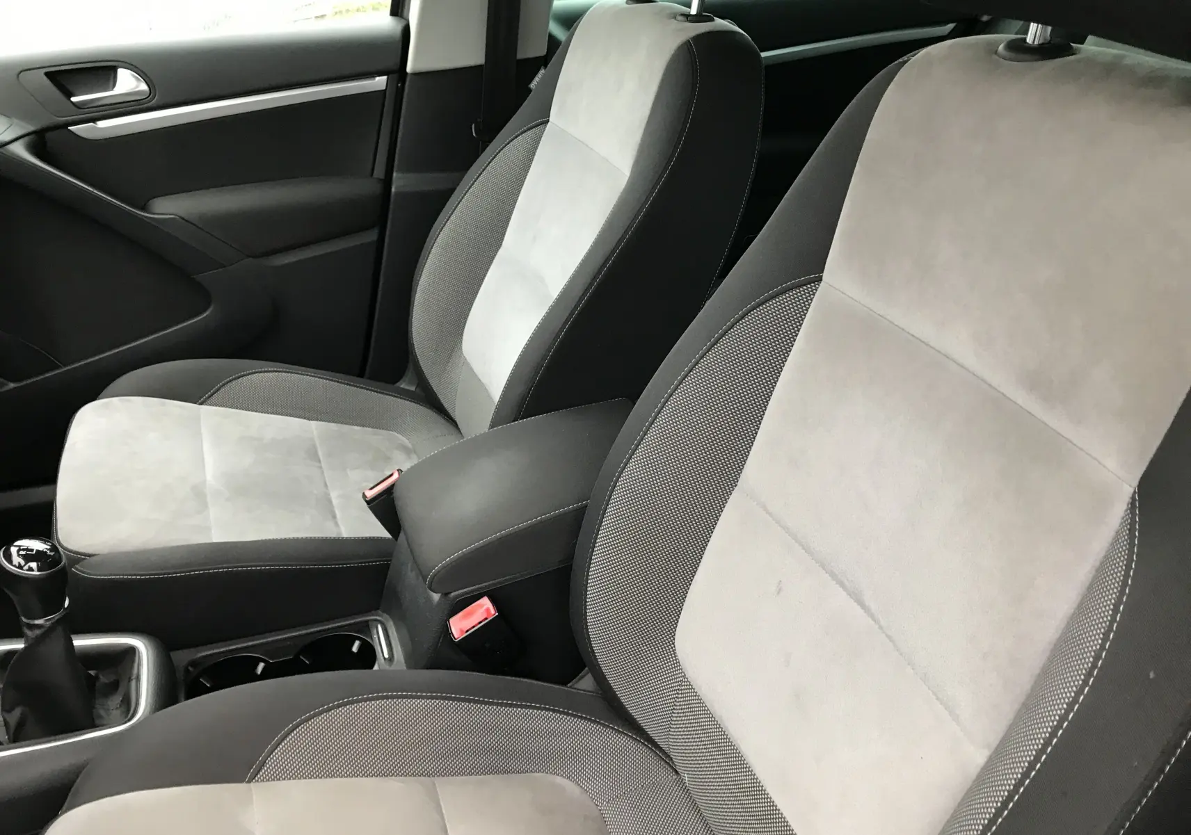 Intérieur du Volkswagen Tiguan Sportline 2012, sièges tissu gris clair et foncé, levier de vitesse manuel visible côté gauche.